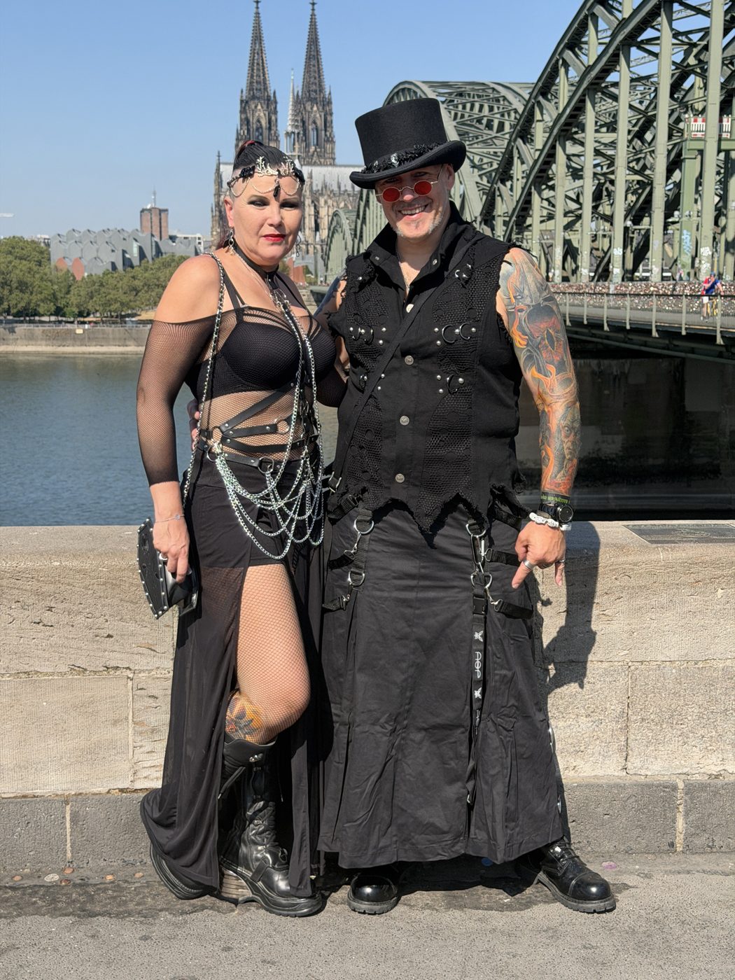 Gerrit und Alexandra Oertgen in schwarzer Festival-Kleidung vor der Hohenzollernbrücke und dem Kölner Dom